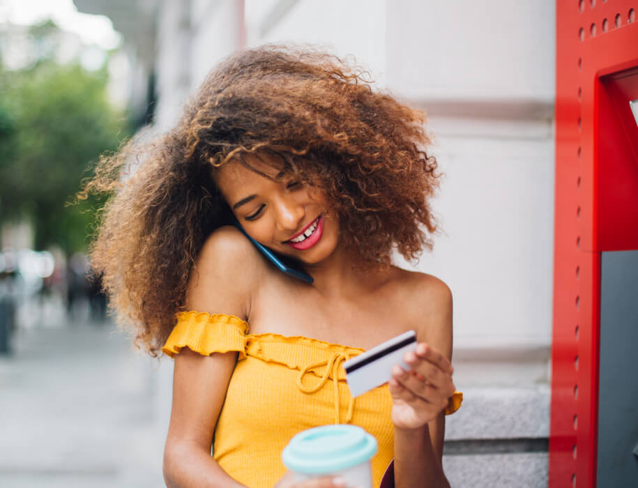 young woman looking at a credit card while talking on phone