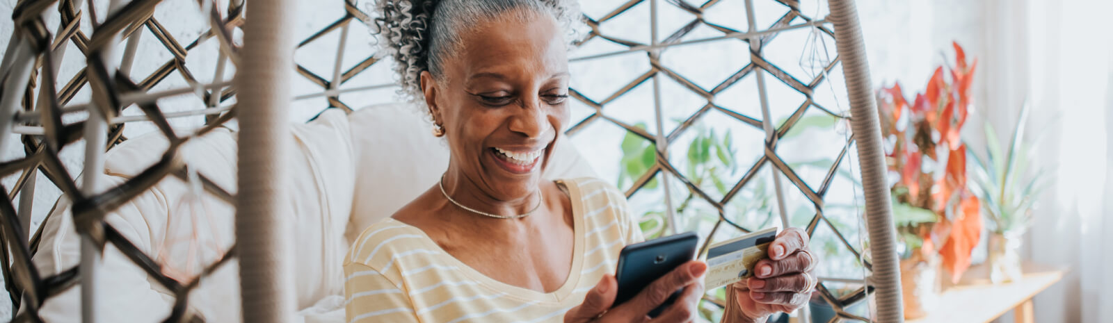 Mature woman looking at a credit card and a smartphone