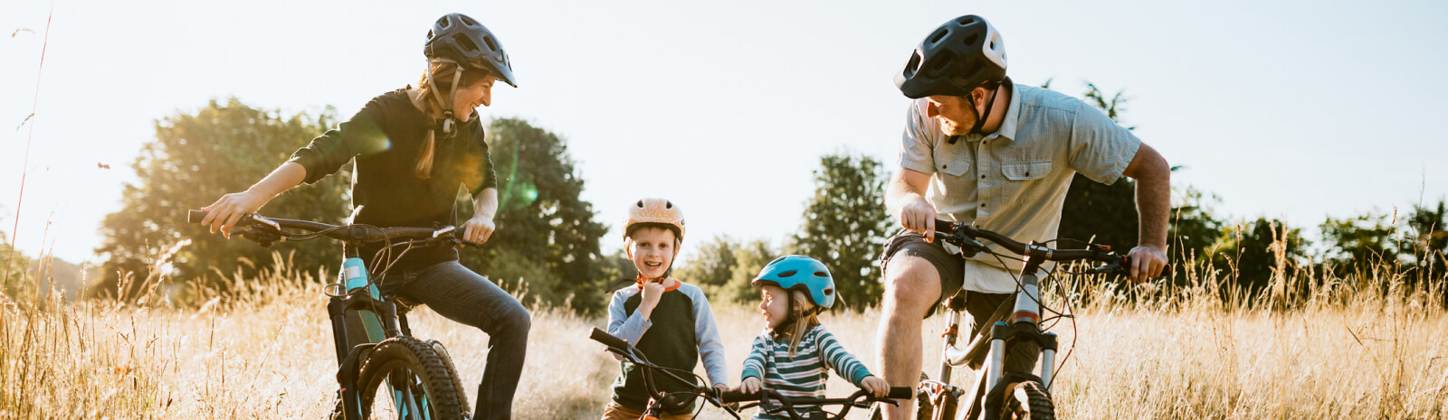 Young family riding bikes in a field